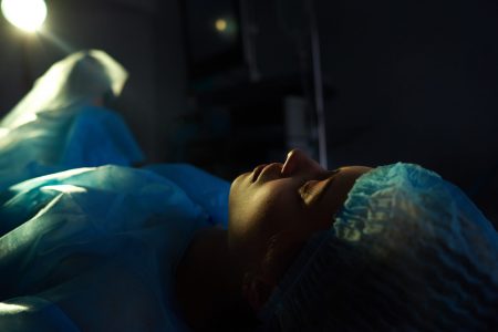 Female patient lying on a surgical table in a dark operating room people life emergency sickness illness vitality medicine hospital clinic concept.